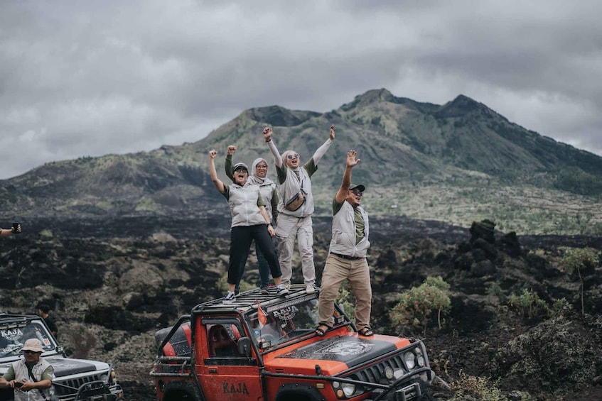 A group of people standing on a vehicle with a mountainous landscape in the background. 3