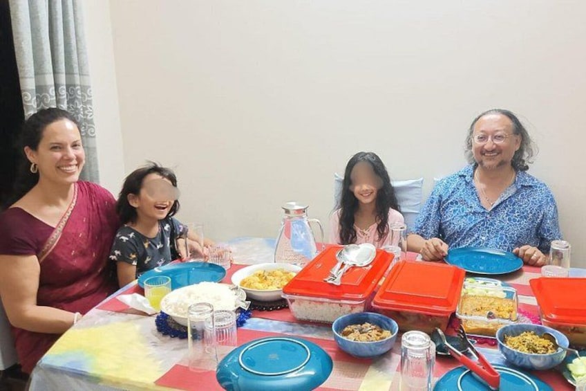 A group of people sitting around a table with various dishes and utensils. 5