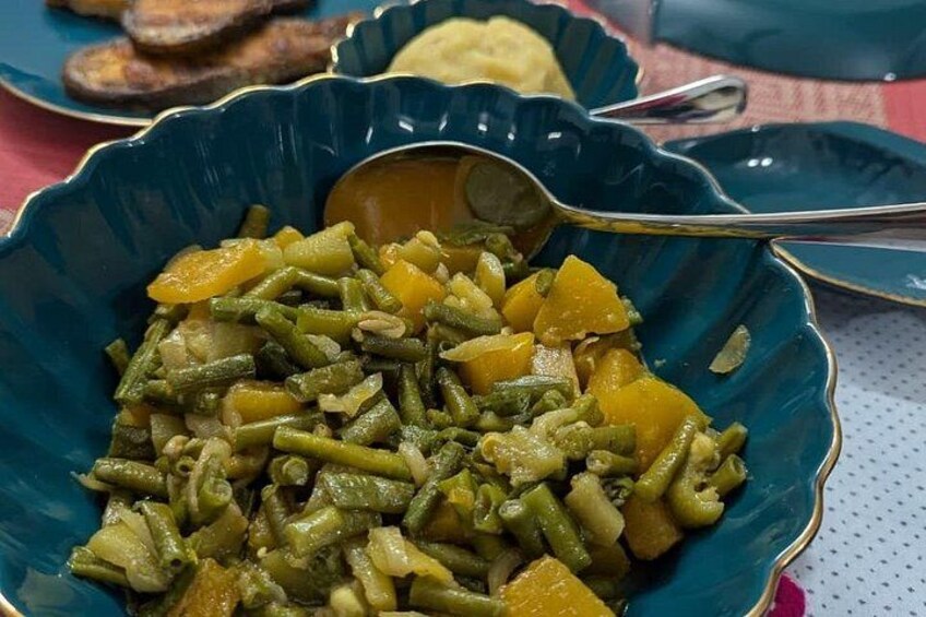 A blue bowl filled with green beans and yellow squash, with a spoon inside. 2