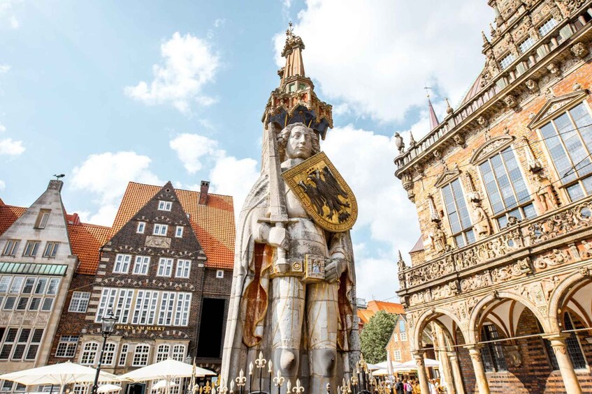 A historic statue in a European town square, surrounded by traditional buildings with intricate facades. 1