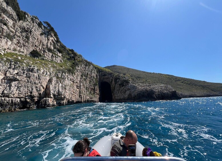 A boat navigating a rocky coastline with a cave entrance. 5