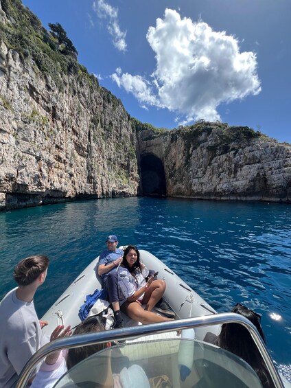 A boat on a clear blue sea with rocky cliffs and a cave entrance. 2