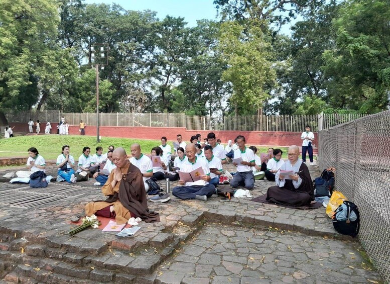 A group of people sitting on stone steps outdoors, some reading and others meditating. 3