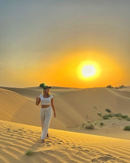 Une personne marchant sur une dune de sable, avec un coucher de soleil en arrière-plan. 1