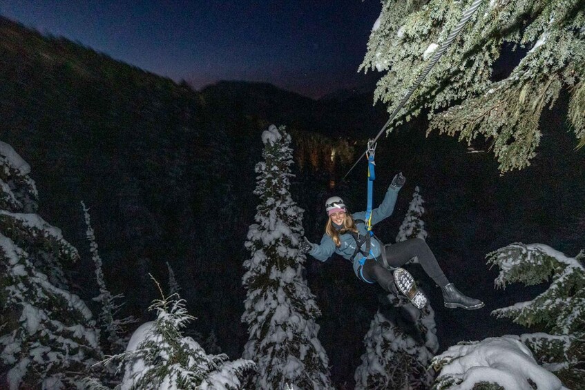 A person bungee jumping from a tree in a snowy forest at night. 1