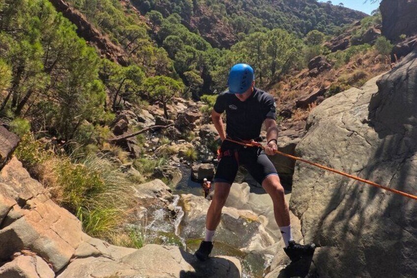 A person rappelling down a rocky cliff with a rope. 1