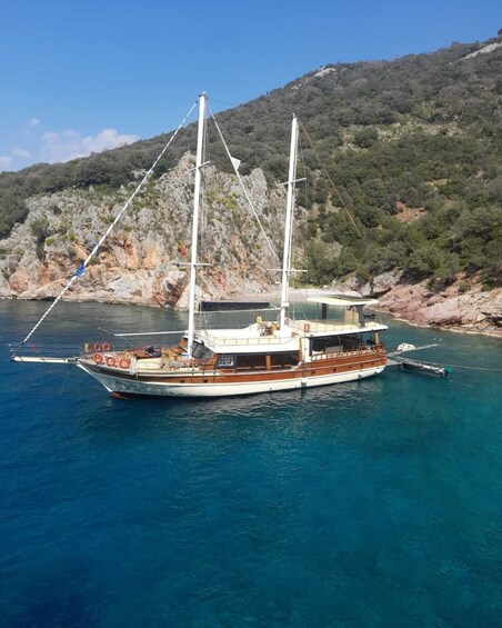 A sailboat docked at a rocky coastal area with clear blue water. 4