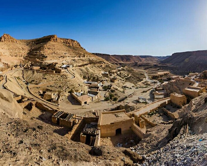 A desert landscape with ancient ruins and a winding road. 1