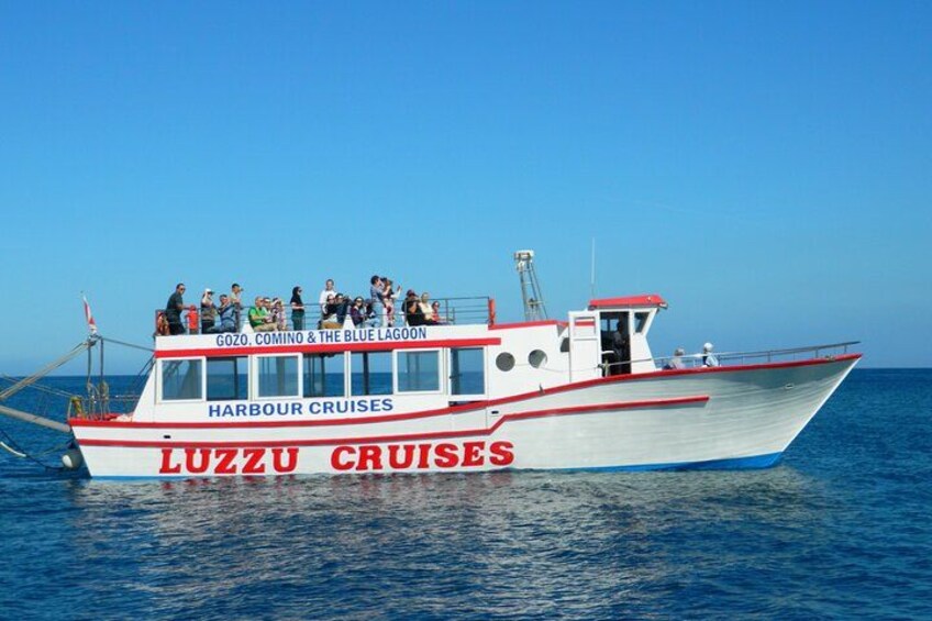 A boat named 'Luzzu Cruises' with 'Harbour Cruises' written on it, sailing on the water. 2