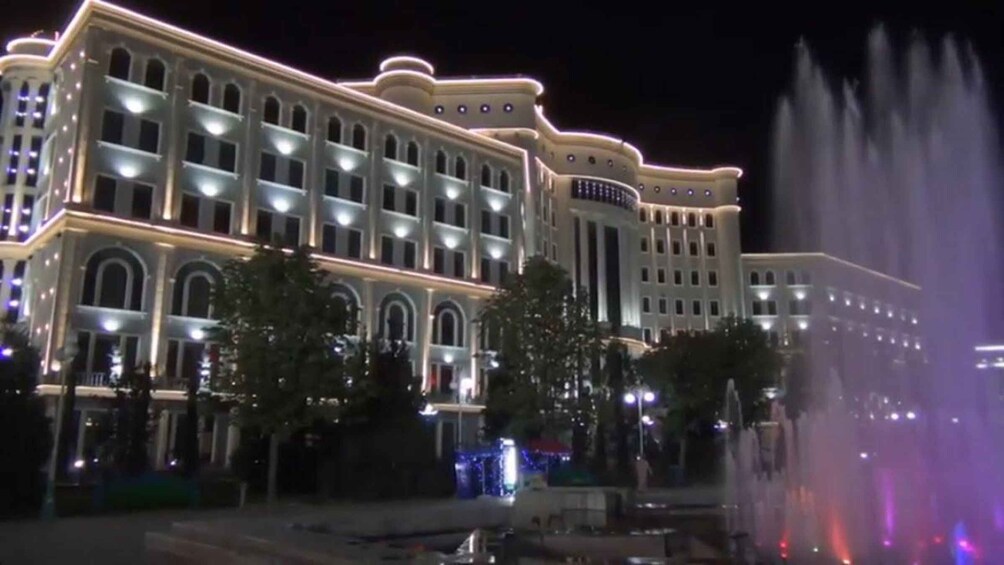 Un edificio grande e iluminado con ventanas arqueadas y una fuente al frente. 5