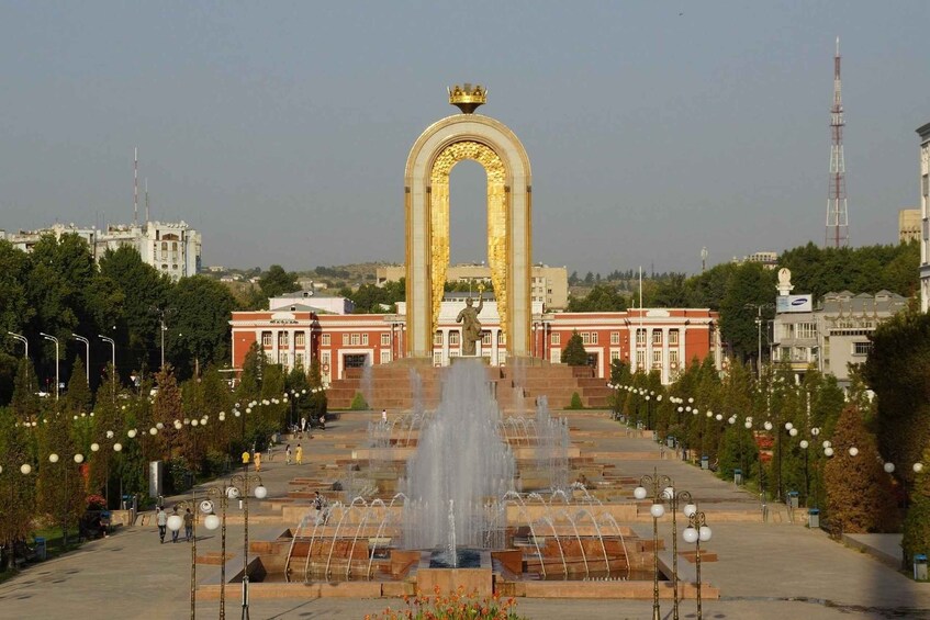 Una gran fuente con chorros de agua, rodeada por un majestuoso arco adornado con una corona dorada en la parte superior, y una estatua en el centro. 2