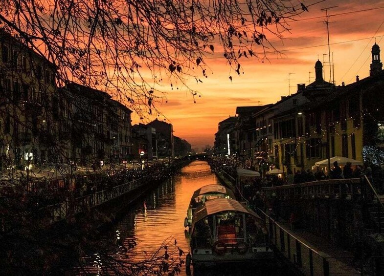A river with boats, buildings, and a sunset sky. 2