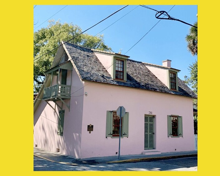 A pink house with green shutters and a balcony. 2