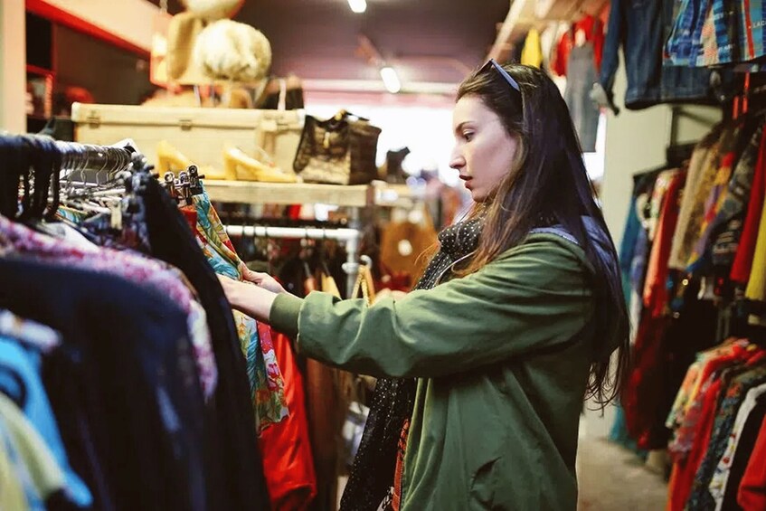 A person browsing through clothing racks in a store. 4