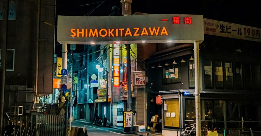 A street with a neon sign reading 'SHIMOKITAZAWA' and a bicycle parked outside a building. 3