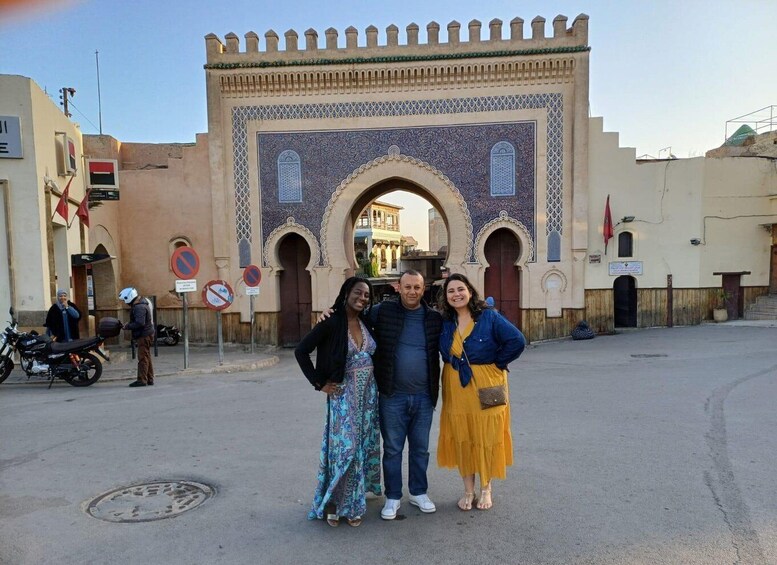 A group of people standing in front of a historic gate with intricate tile work and arches. 2