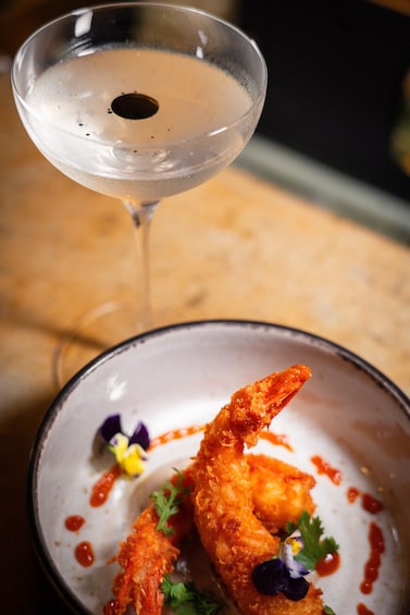 A martini glass and a bowl of fried shrimp with garnish. 4