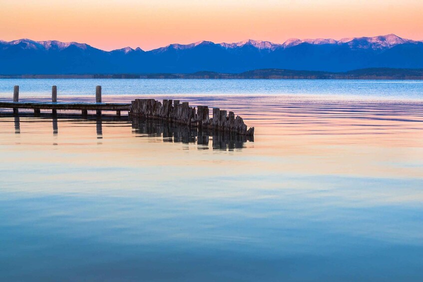 A calm lake with a wooden dock extending into the water, surrounded by mountains in the background. 4