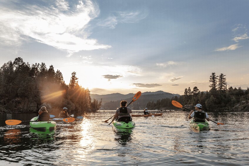 Three kayakers on a calm river with a forested landscape in the background. 1