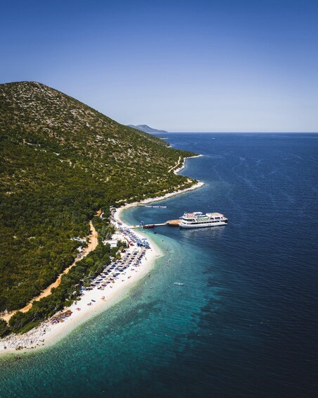 A coastal landscape with a beach, a boat, and a mountainous backdrop. 4