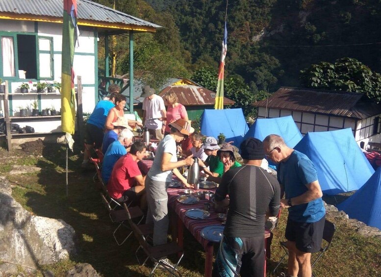 A group of people gathered around a table outdoors, possibly at a picnic or outdoor event. 5