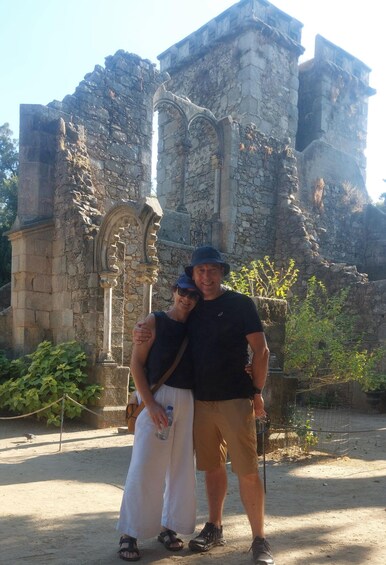 Two people standing in front of an ancient stone structure with arches and columns. 5