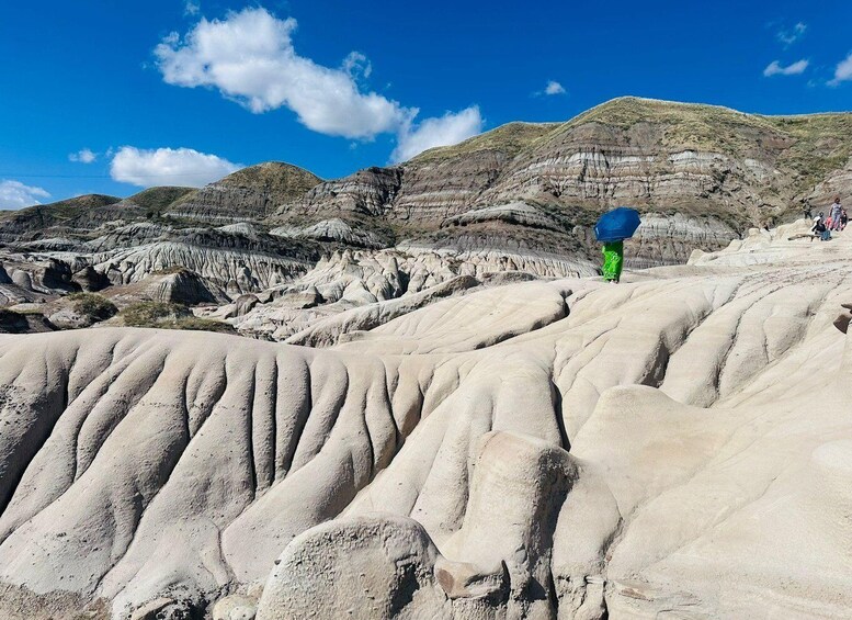 A person hiking on a rocky terrain with layered geological formations. 4