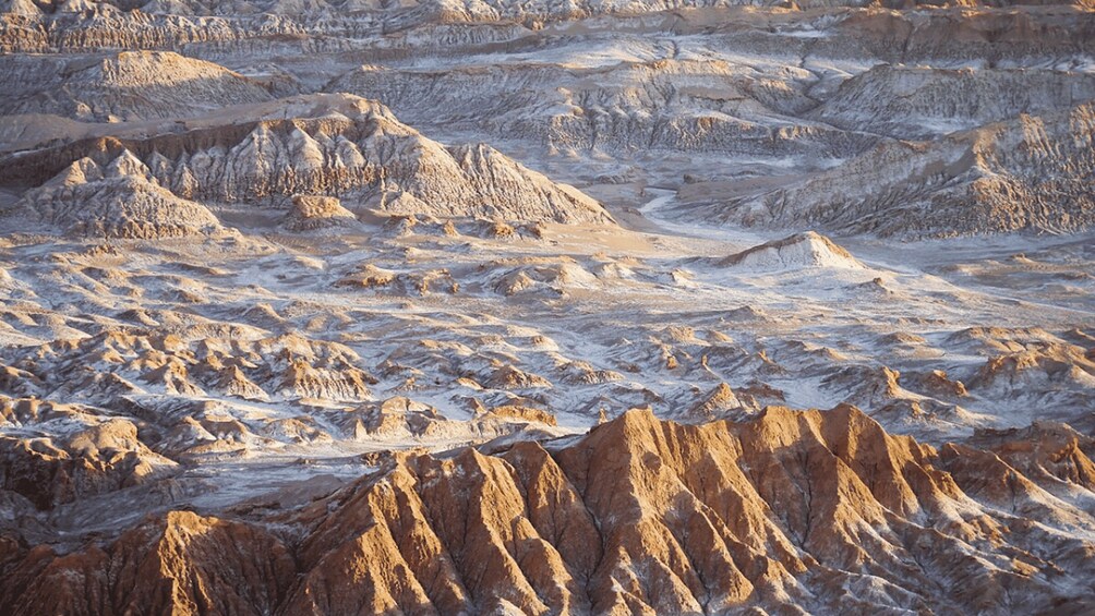 A rugged, arid landscape with layered rock formations and a prominent ridge in the foreground. 5