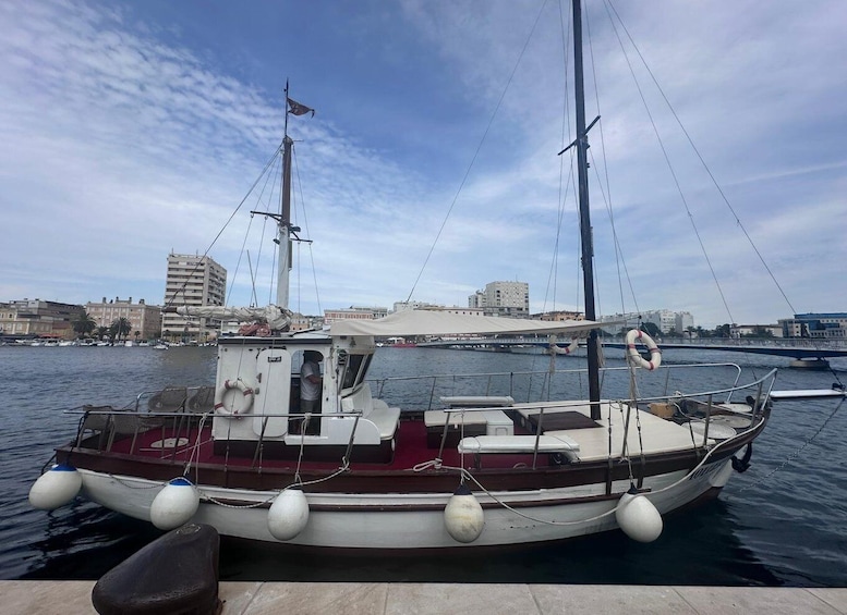A small sailboat docked at a marina with buildings in the background. 2