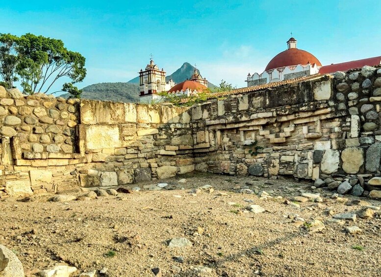 An ancient stone wall with a church and domed buildings in the background. 2