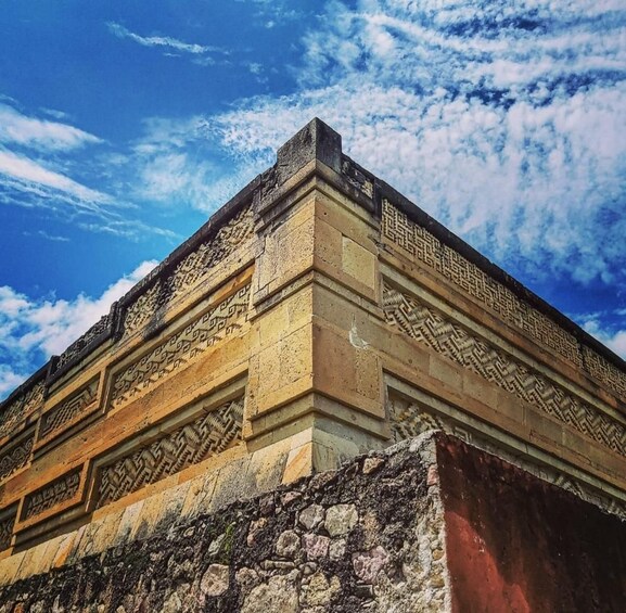 A stone structure with intricate carvings and a clear blue sky with clouds. 1