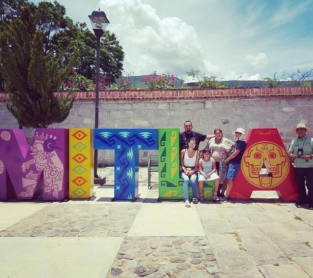 A group of people posing in front of colorful, stylized letters and a stone wall. 3