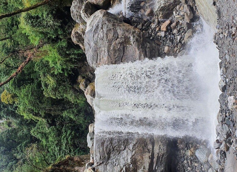 A waterfall cascading over a rocky cliff surrounded by dense green forest. 3