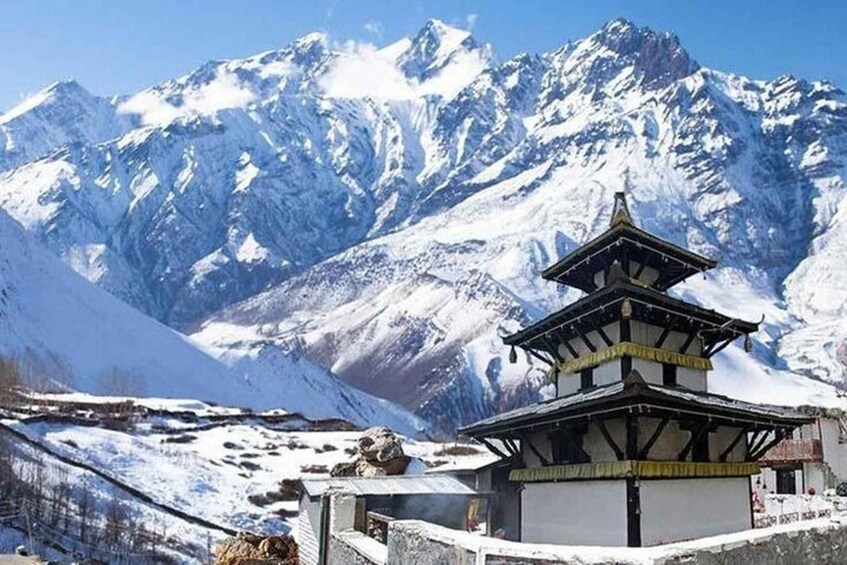 A snow-covered mountain range with a traditional multi-tiered building in the foreground. 1