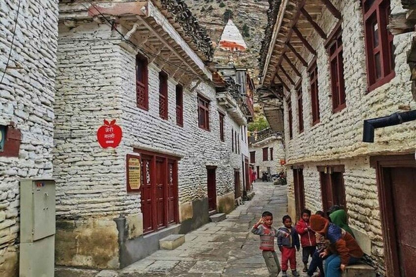 A narrow stone street with traditional buildings, a red sign, and a group of people. 5