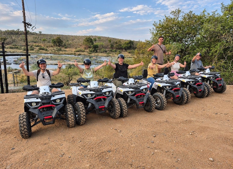 A group of people on ATVs in a natural setting with a river and hills in the background. 2