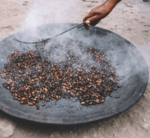 A person roasting coffee beans on a flat surface. 2
