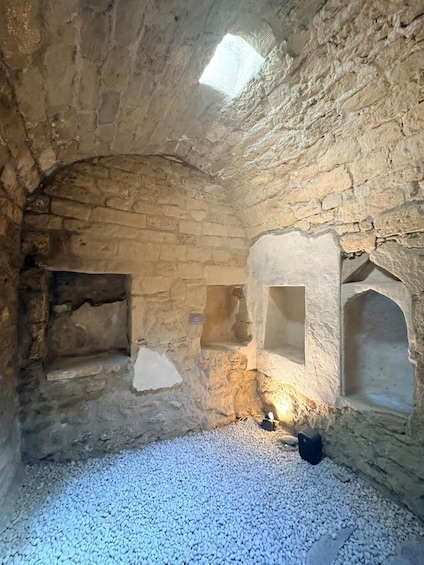 An ancient stone structure with arched niches and a gravel floor. 2