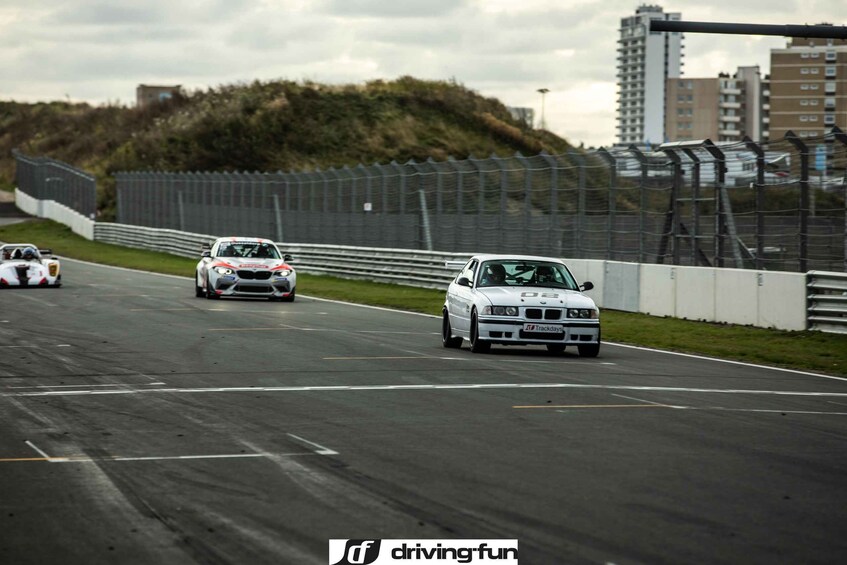 Una pista de carreras con coches, una valla y edificios al fondo. 1
