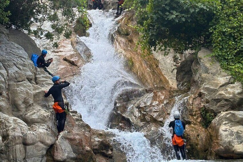 A group of people kayaking in a rocky canyon with a waterfall. 5