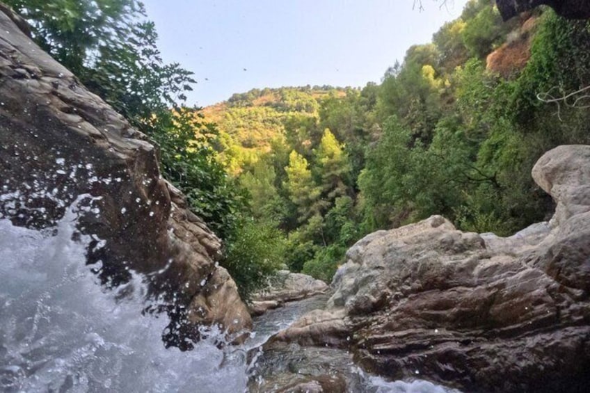 A river flowing through a rocky gorge with lush green vegetation and hills in the background. 4