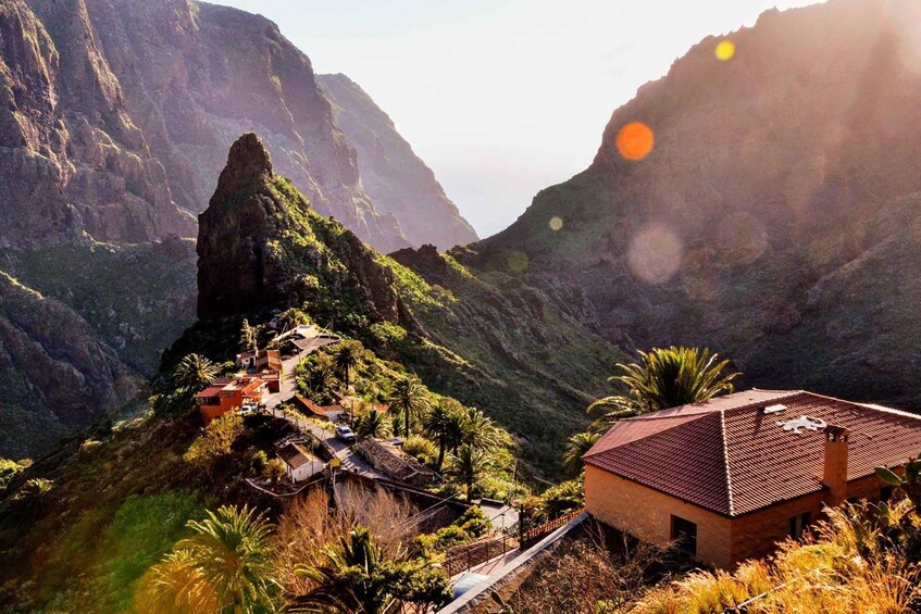 A mountainous landscape with a village nestled among the cliffs, featuring traditional houses and a prominent rock formation. 3