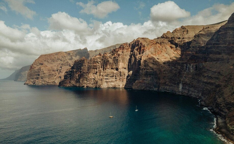 A coastal cliff with a clear blue sea and a small boat. 5