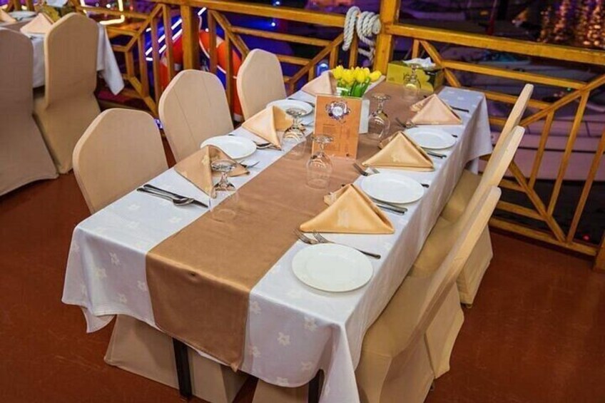A dining table set with white plates, gold napkins, and a brown table runner. 4