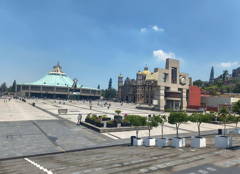 A plaza with a large church, a clock tower, and a modern building. 1