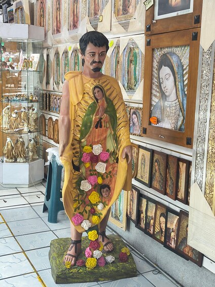 A statue of a religious figure with a green robe and flowers. 5