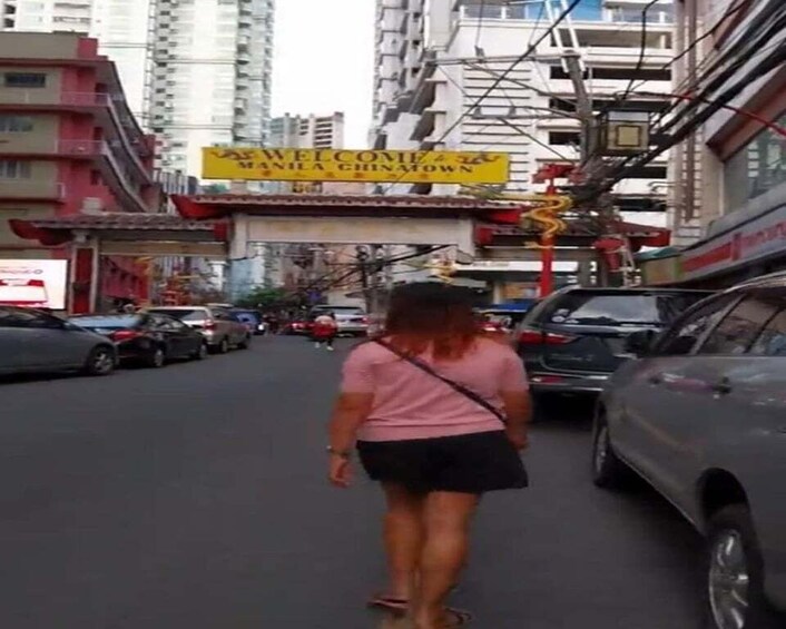 A person walking down a street lined with parked cars and buildings. 5