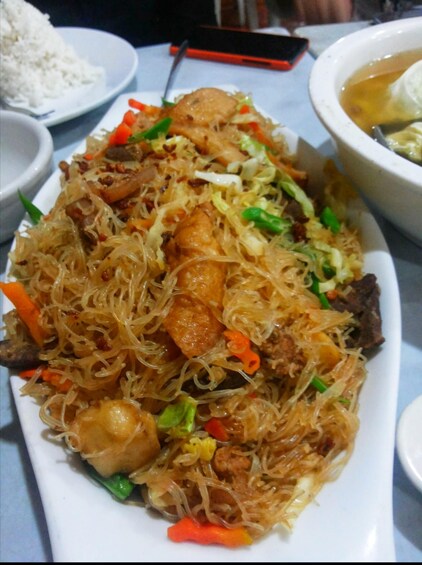 A plate of stir-fried noodles with vegetables and meat. 1