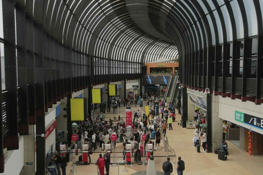 A busy indoor public space with a curved ceiling, multiple levels, and various signs and banners. 5
