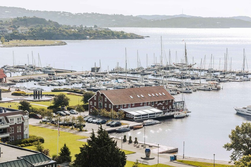 A marina with multiple boats docked, a large building with a red roof, and a grassy area with a statue. 2